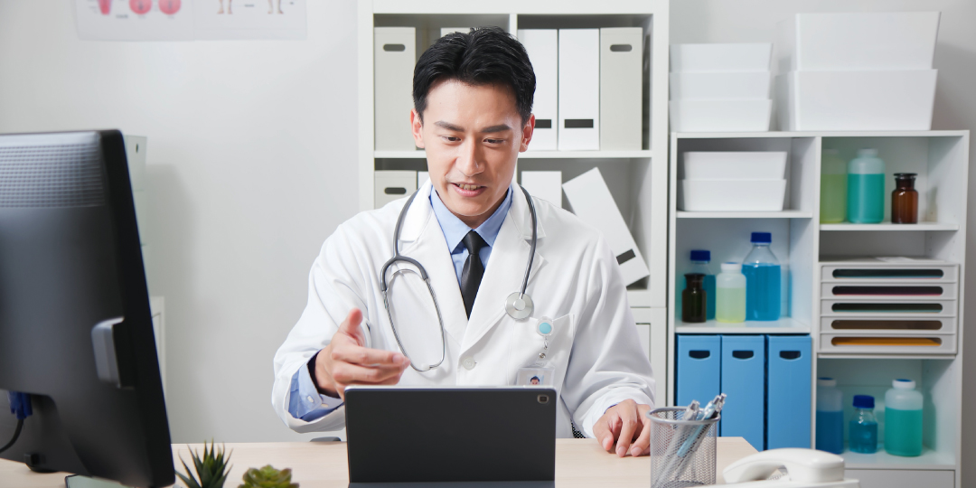 doctor speaking with patient from his desk via telehealth 